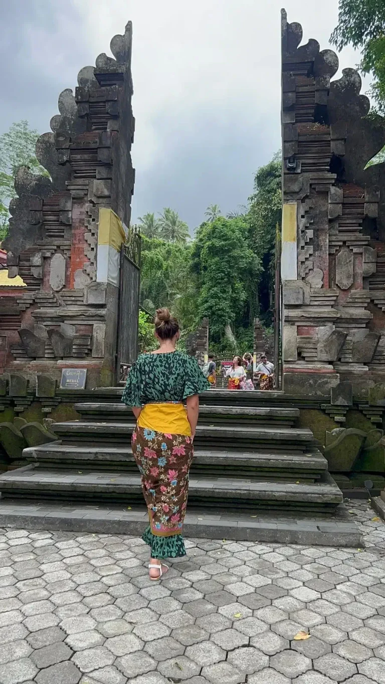 Manon Pugliese, Thérapeute Neuro-Coach, montant vers une porte de temple balinais ornée.